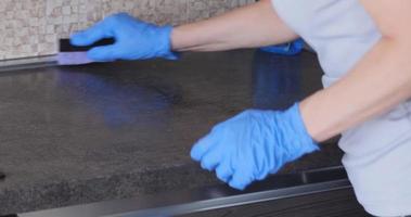 Cleaning the kitchen countertop with detergents in blue gloves video