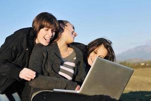 grupo de adolescentes trabajando en una laptop al aire libre foto