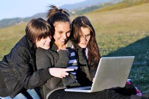 grupo de adolescentes trabajando en una laptop al aire libre foto