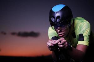 atleta de triatlón montando bicicleta rápido por la noche foto