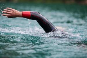 triathlon athlete swimming on lake wearing wetsuit photo