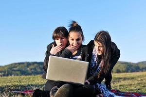 grupo de adolescentes trabajando en una laptop al aire libre foto