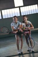 young girls playing tennis game indoor photo