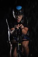 triathlon athlete riding bike  fast on rainy night photo