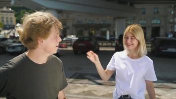 Two young teens talk to each other outside with backpacks video