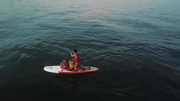 People kneel on paddle board on large lake video