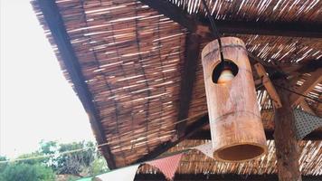 Rustic lamp sways in the breeze under a thatched roof video