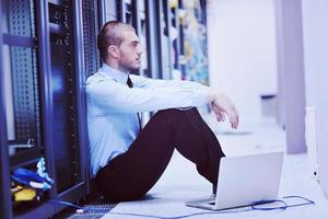 businessman with laptop in network server room photo