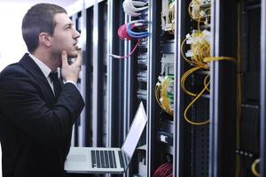 businessman with laptop in network server room photo