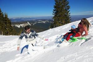 familia divirtiéndose en la nieve fresca en invierno foto