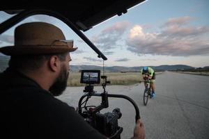 videógrafo tomando una foto de acción de un atleta de triatlón mientras monta en bicicleta