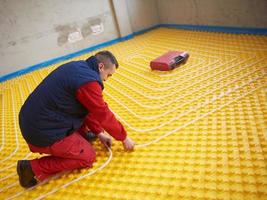 workers installing underfloor heating system photo