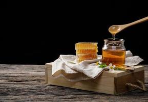 abeja de miel en tarro y panal con cucharón de miel y flor en mesa de madera, productos de abeja por concepto de ingredientes naturales orgánicos, espacio de copia para su texto foto