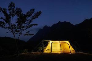 Glowing yellow tent in the mountains with cloud in natural park, Tourism concept photo