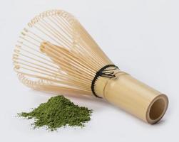 Batidor de alambre japonés con montón de polvo de té verde matcha aislado sobre fondo blanco, producto orgánico de la naturaleza para la salud con estilo tradicional foto