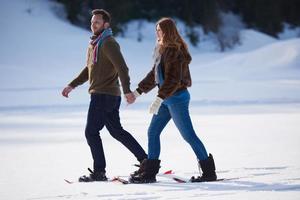 pareja divirtiéndose y caminando con raquetas de nieve foto