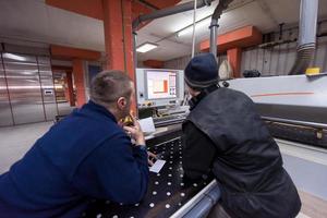 carpenters calculating and programming a cnc wood working machine photo