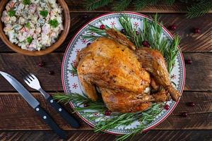 Baked whole chicken or turkey for Christmas. New Year's table with decoration, homemade roasted chicken, wine and salad. Top view photo