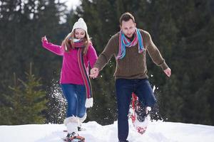 pareja divirtiéndose y caminando con raquetas de nieve foto