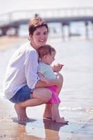 mamá y bebé en la playa se divierten foto