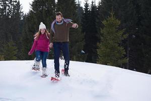 pareja divirtiéndose y caminando con raquetas de nieve foto