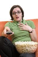 young woman eat popcorn and watching tv photo