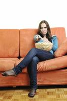 young woman eat popcorn on orange sofa photo