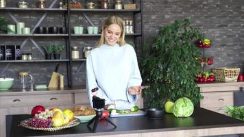 Young woman in a kitchen with fresh ingredients and smart phone device video