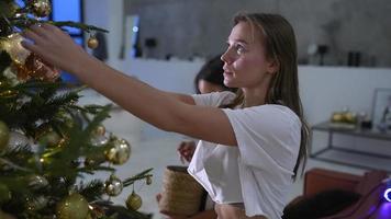 ragazza amici nel pigiama decorare un' Natale albero nel appartamento video