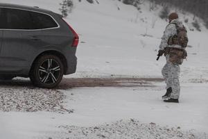 guerra de invierno en las montañas árticas. operación en condiciones frías. soldado en uniforme camuflado de invierno en el ejército de guerra moderno en un día de nieve en el campo de batalla del bosque con un rifle. enfoque selectivo foto