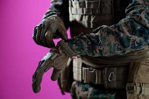 closeup of soldier hands putting protective battle gloves pink background photo