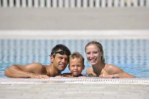 familia joven feliz divertirse en la piscina foto