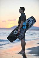 Portrait of a young  kitsurf  man at beach on sunset photo