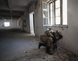 soldier in action near window changing magazine and take cover photo