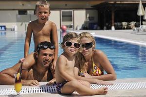 familia joven feliz divertirse en la piscina foto