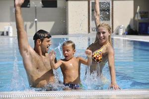 familia joven feliz divertirse en la piscina foto