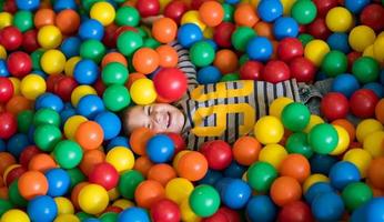 niño divirtiéndose en la piscina con bolas de colores foto