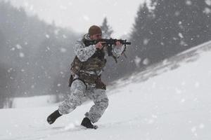 guerra de invierno en las montañas árticas. operación en condiciones frías. soldado en uniforme camuflado de invierno en el ejército de guerra moderno en un día de nieve en el campo de batalla del bosque con un rifle. enfoque selectivo foto