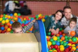 parents and kids playing in the pool with colorful balls photo