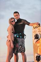 pareja de surf posando en la playa al atardecer foto