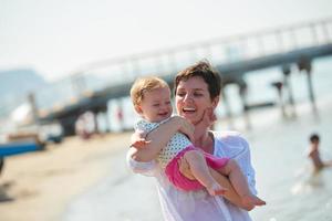 mamá y bebé en la playa se divierten foto