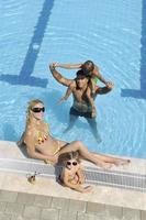 familia joven feliz divertirse en la piscina foto