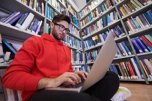 the students uses a notebook, laptop and a school library photo