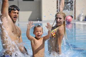 familia joven feliz divertirse en la piscina foto