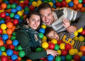 padres e hijos jugando en la piscina con bolas de colores foto