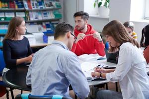 grupo de estudiantes trabajando juntos en un proyecto escolar en una tableta en una universidad moderna foto