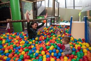 madre joven con sus hijos en una sala de juegos para niños foto