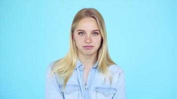 Young blonde woman in front of a light blue backdrop expresses different emotions video