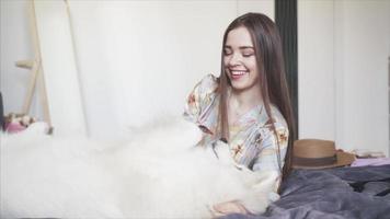 Big white dog on bed while girl dresses up video