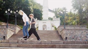 Tonårs pojke och flicka hängande ut på de parkera med en skateboard video